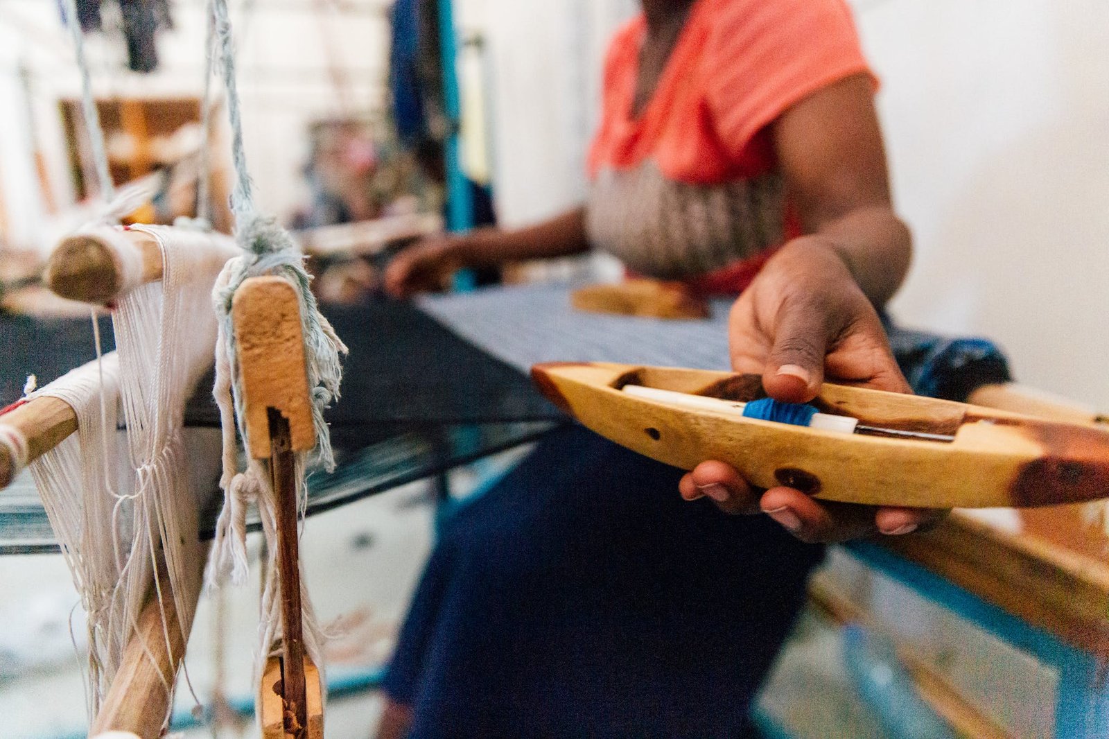 Crop black female artisan working on manual loom in workshop